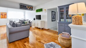 Una sala de estar moderna con un sofá gris, un mueble blanco y un televisor.