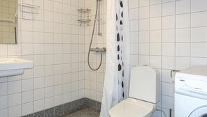 Une salle de bain avec des toilettes, un lave-linge et une douche.