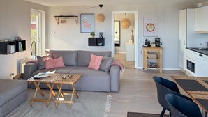 Un salon moderne avec un canapé gris, une table basse et un coin repas comprenant une chaise noire.