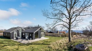 Et moderne hus med en stor terrasse, et spiseområde og havudsigt.