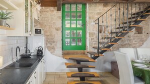Una cucina con una porta verde, una scala e una sala da pranzo con un tavolo apparecchiato per due.