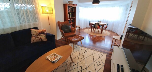 Un soggiorno con divano, poltrona, tavolino e zona pranzo con sedie e tavolo.
