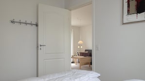 Ett sovrum med en säng, ett sängbord, en lampa och en dörr.