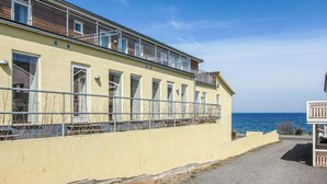 En gul byggnad med många fönster och balkonger med utsikt över havet.