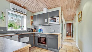 Eine moderne Küche mit grauen Schränken, einem eingebauten Ofen und einem Fenster mit Pflanzen.