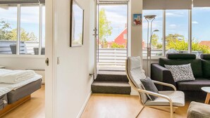 Een moderne hotelkamer met een bed, een zithoek met een bank en stoelen, een trap en grote ramen met uitzicht.