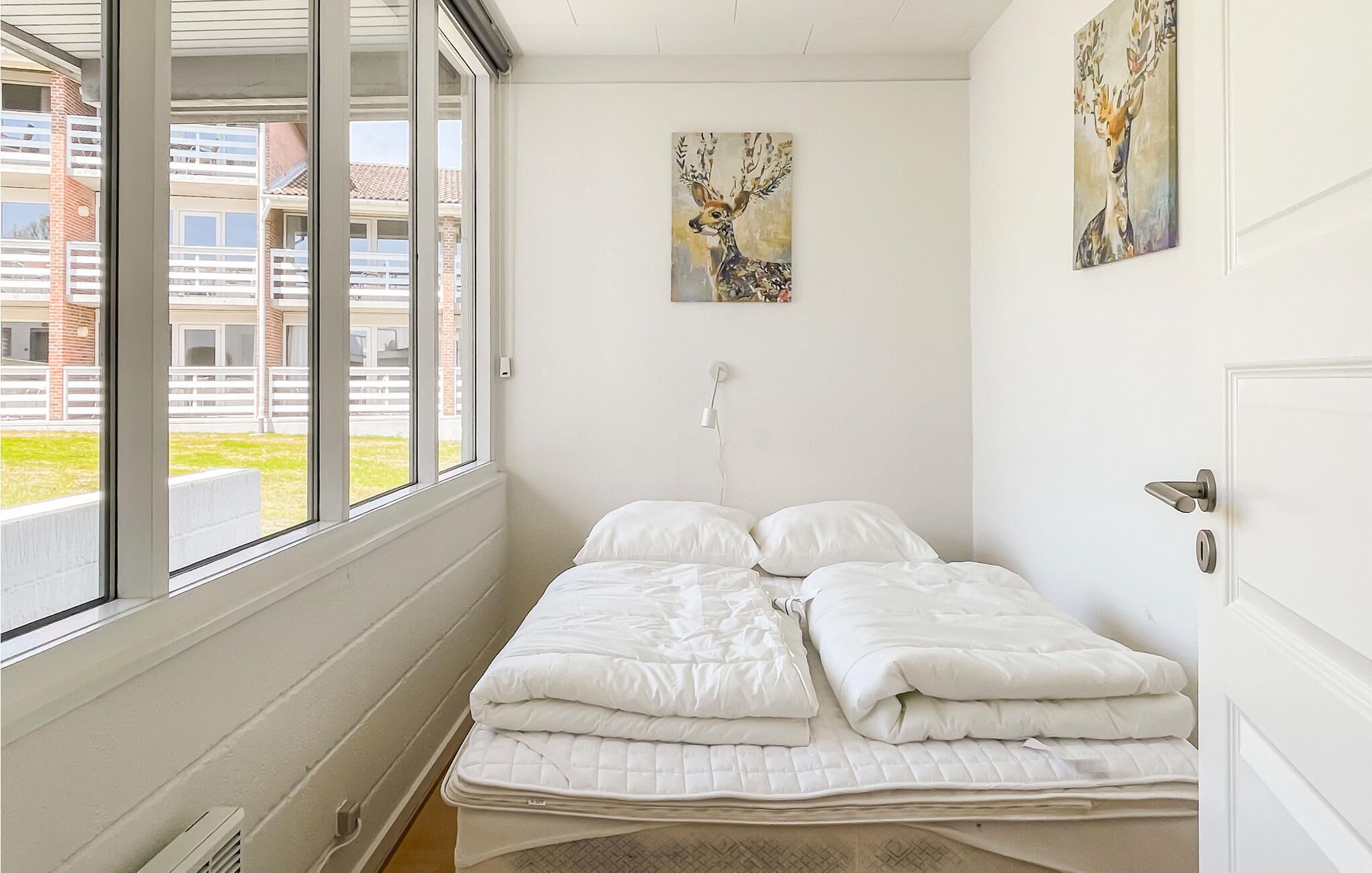 Une chambre à coucher avec un lit, une fenêtre et deux tableaux accrochés au mur.