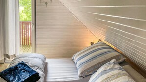 A small, cozy room with a bed, a window, and a view of greenery outside. - Ferienhaus 12 in Kirchheim (Kirchheim)