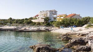 Un hôtel situé sur la côte, avec plusieurs étages, un rivage rocheux et une eau cristalline.