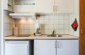 Enjoy cooking in this fully equipped kitchen with a coffee maker, sink, refrigerator, microwave, and dish rack.