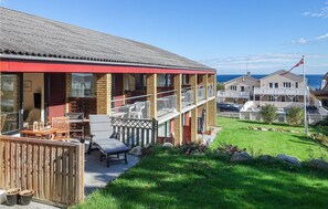 Situated in a coastal area, this two-story residence features a well-maintained lawn and garden, a balcony, and a driveway leading to the entrance.
