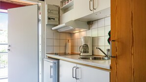 A compact kitchen with a built-in oven, a coffee maker, and a sink.