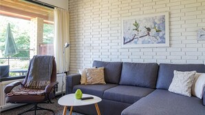 A modern living room with a grey sofa, a small white table, and a chair with a throw blanket.