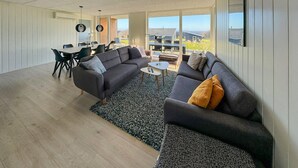 Un salon moderne comprenant un ensemble de canapés, une table basse et un coin repas avec des chaises et une table.
