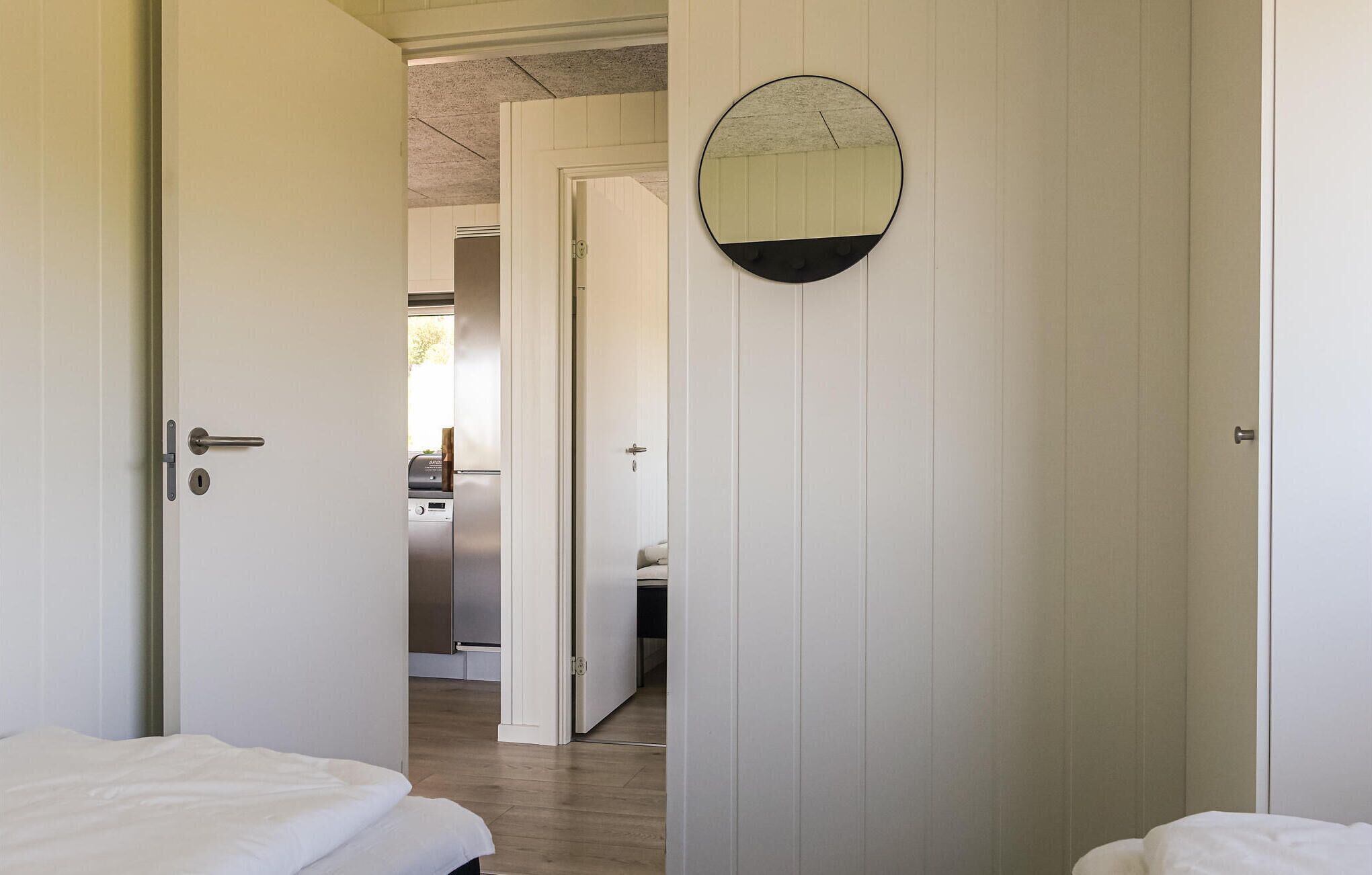 Ett hotellrum med en säng, en dörr som leder till ett badrum och ett kök som syns genom en öppen dörr.