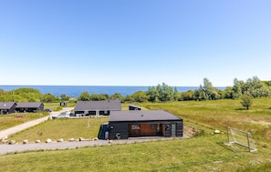 A modern cabin-style building with a large deck and a view of the ocean.