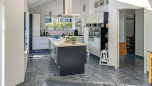 Eine moderne Küche mit Kochinsel, integrierten Geräten und Blick ins Freie.