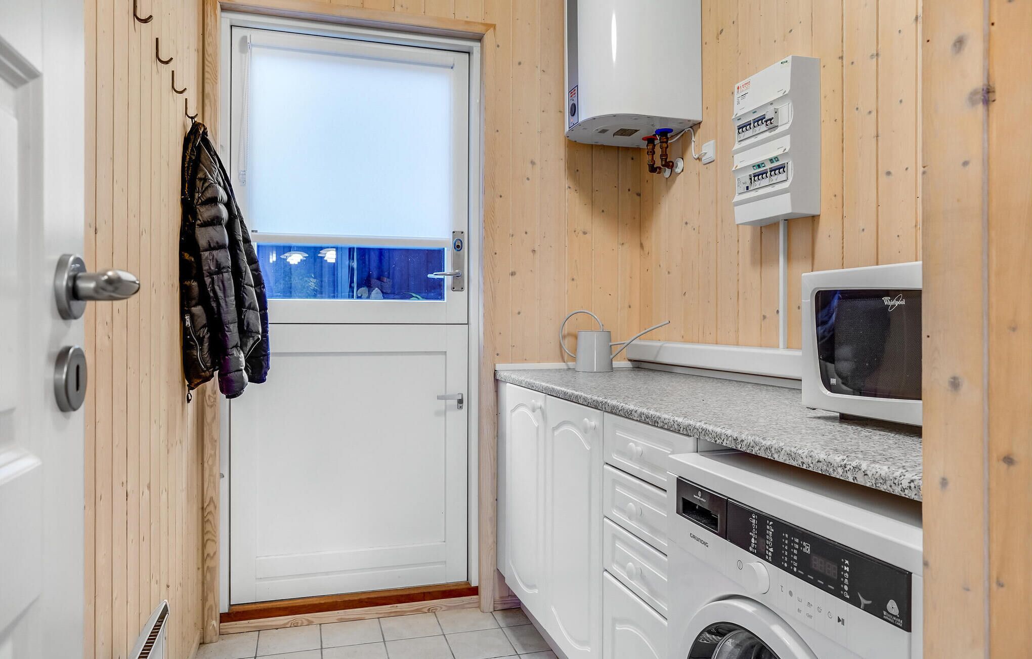 Een kleine keuken met een wasmachine, een magnetron en een boiler.