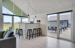 A modern interior with a kitchen area, bar stools, and a patio with outdoor seating. - Gorgeous home in Sydals with kitchen (Sydals)