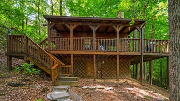 A wooden cabin with a balcony, surrounded by trees.
