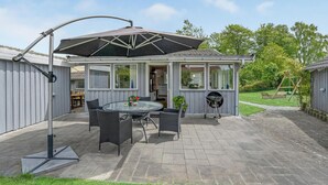 Un patio couvert avec une table et des chaises, un barbecue et une balançoire.
