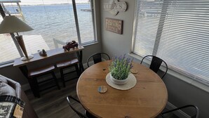 A dining area with a round wooden table, benches, and chairs. There is a potted plant on the table, and a lamp on a side table.