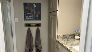 A kitchen with beige cabinets, a granite countertop, and a backsplash. There is a towel rack with two towels and a motivational quote on the wall.