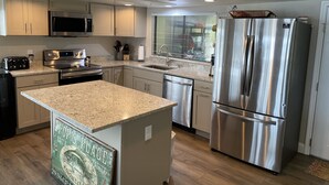A modern kitchen with stainless steel appliances, granite countertops, and a central island.