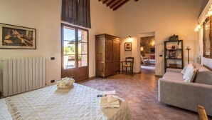 A cozy room with a bed, a chair, a sofa, a wooden wardrobe, and a stone wall. - 1 bedroom nice home in Siena (Siena)