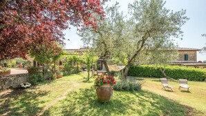 A garden with a large pot of red flowers, a hammock, and two lounge chairs. - 1 bedroom nice home in Siena (Siena)