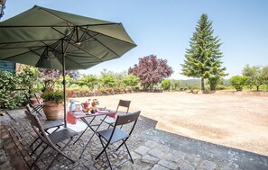 A patio with a table and chairs under a large umbrella, surrounded by potted plants and trees. - 1 bedroom nice home in Siena (Siena)