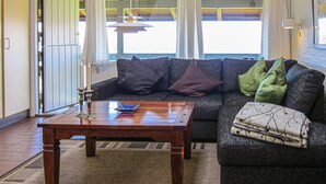 Een woonkamer met een bank, een houten salontafel en uitzicht door een raam.