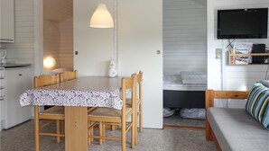 Une pièce de taille modeste comprenant une table à manger, des chaises, un canapé, un téléviseur et un coin cuisine.