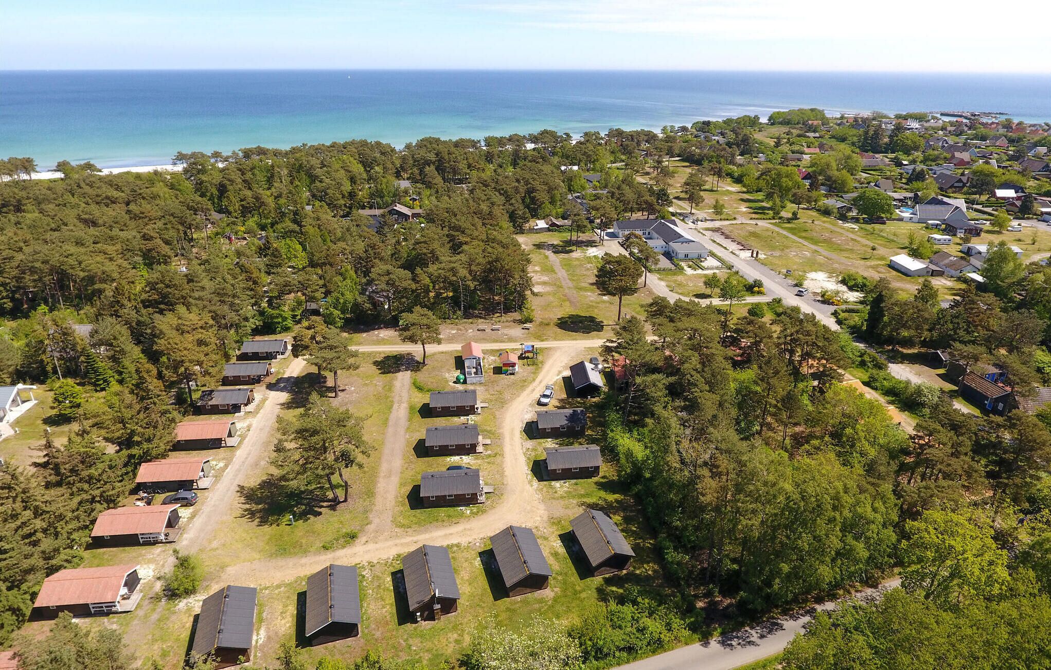 An aerial view of a residential area with houses, a beach, and a clear view of the ocean.