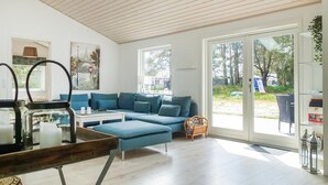 Un soggiorno moderno con un divano angolare blu, un tavolino in vetro e un soffitto in legno.