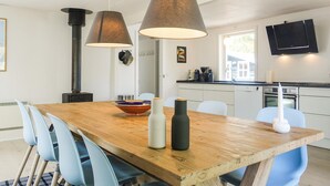 Una cucina moderna con un tavolo di legno, sedie blu e lampade a sospensione.