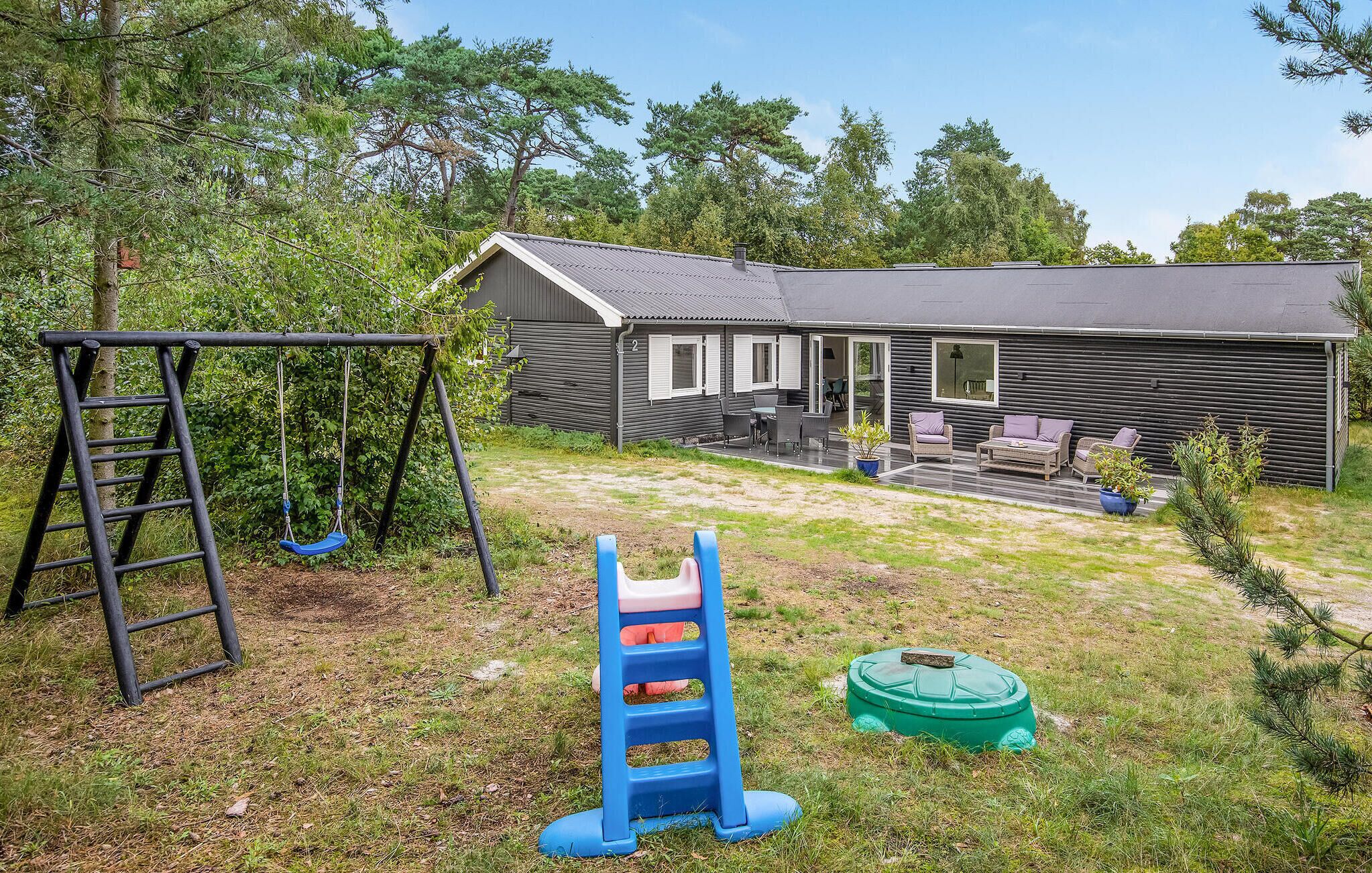 A residential property with a patio area, a swing set, and a small play structure.