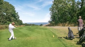 Ein Golfplatz mit freiem Blick auf das Meer im Hintergrund.