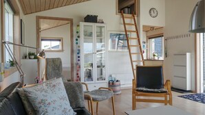 Ein gemütliches Wohnzimmer mit Sofa, Sesseln und einer Wendeltreppe zu einem Schlafboden.