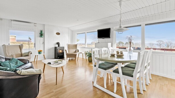 A spacious room with a dining area, a fireplace, and large windows offering a view. - Beautiful home in Allinge with WiFi (Allinge)
