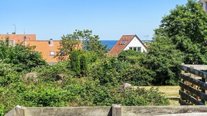 Ett bostadsområde med ett trästaket, frodig grönska och hus med röda tegeltak.