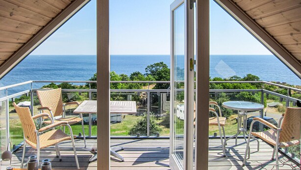 A balcony with a view of the ocean, wicker chairs, and a table. - 2 bedroom lovely apartment in Gudhjem (Gudhjem)