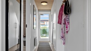 Een gang met uitzicht naar buiten, een radiator en een hangende tas.