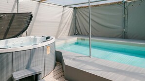 Un bain à remous avec des marches, une piscine et un espace couvert doté d’un auvent.