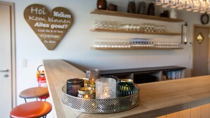 Un espace bar avec un plateau rempli de verres décoratifs, des étagères où sont rangés des verres, et un panneau en forme de cœur avec une inscription.