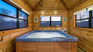 A wooden cabin with a hot tub, large windows, and a warning sign about no lifeguard on duty. - Smoky Mountain Fall Colors Private Pool Hot Tub Theater and Cozy Mountain Escape (Cosby)