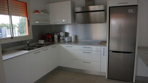 Una cocina moderna con armarios blancos, electrodomésticos de acero inoxidable y un horno empotrado.