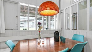 Una sala de conferències amb una taula de fusta, cadires verda blavosa, una llum penjant taronja gran i un ram de flors.