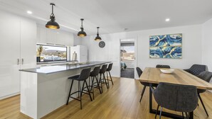 Una cocina moderna con una isla central, taburetes de bar e iluminación colgante.