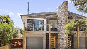 Una casa moderna de dos pisos con balcón, ventanas amplias y garaje.